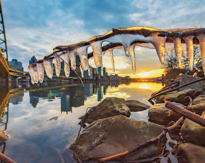 Icicles frame the rising sun along the still waters of the Monongahela River in Pittsburgh - Various Prints