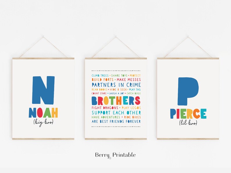 May include: Two colorful prints with the names Noah and Pierce, with the text "big bro" and "lil bro" underneath. The prints feature the first letter of each name in a large blue font, with the rest of the name in a rainbow font. The middle print features a list of things brothers do together, such as "climb trees", "share toys", "build forts", "make messes", "partners in crime", "read books", "hide and seek", "play tag", "count stars", "laugh a lot", "catch bugs", "fight dragons", "play legos", "support each other", "have adventures", "ride bikes", and "are best friends forever".
