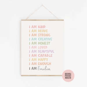 May include: A printable wall art design with the text "I am kind, I am brave, I am strong, I am creative, I am honest, I am loved, I am beautiful, I am capable, I am happy, I am enough, I am Emilia". The text is in a rainbow of colors and is printed on a white background.