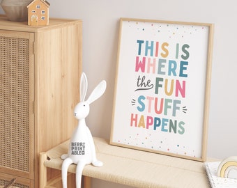 May include: A framed print with a white background and colorful text that reads "This is where the fun stuff happens". The print is surrounded by a light wood frame and has a white background with colorful confetti.