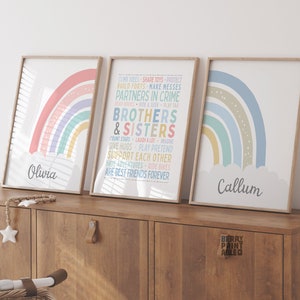 May include: Three framed rainbow prints with the names Olivia and Callum at the bottom. The middle print has text that reads "CLING TREES SHARE TOYS PROTECT BUILD FORTS MAKE MESSES PARTNERS IN CRIME READ BOOKS HAVE A LOT PLAY TAG BROTHERS & SISTERS COUNT STARS LAUGH A LOT IMAGINE GIVE HUGS PLAY PRETEND SUPPORT EACH OTHER HAVE ADVENTURES RIDE BIKES ARE BEST FRIENDS FOREVER"