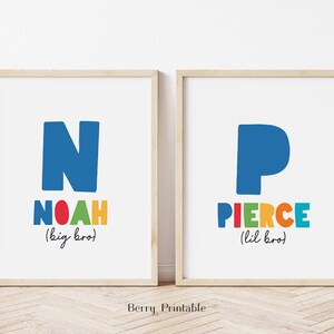 May include: Two framed prints with colorful letters spelling out the names Noah and Pierce. The prints are on a white background and have the words "big bro" and "lil bro" written below the names.