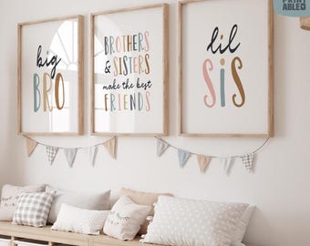 May include: Three framed prints with text: "big BRO", "BROTHERS & SISTERS make the best FRIENDS", and "lil SIS". The prints are in wooden frames, with a garland of small flags below. Pillows and storage bins are visible below the prints.