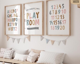 May include: Three framed prints with wooden frames. The prints display the alphabet, numbers 1-20, and the words "PLAY ROOM". The prints are in a child's room, with a garland and pillows.