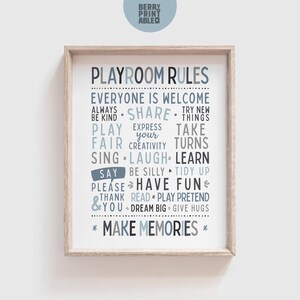 May include: A framed print featuring "PLAYROOM RULES" in blue and grey text. The print includes positive messages such as "Share," "Laugh," and "Have Fun." The print is presented in a light wood frame.