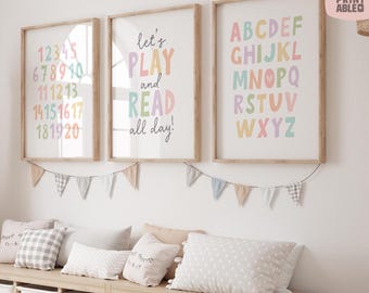 May include: Three framed prints with pastel-colored numbers, letters, and a motivational quote. The prints are in wooden frames and are hanging above a bench with pillows and storage bins. A banner of small flags hangs below the prints.