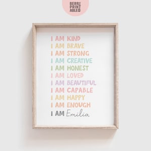 May include: A framed print with a white background and colorful text that reads "I am kind, I am brave, I am strong, I am creative, I am honest, I am loved, I am beautiful, I am capable, I am happy, I am enough, I am Emilia".