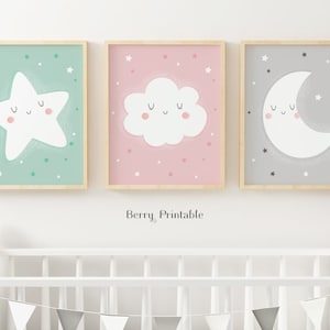 May include: Three framed prints with a green, pink, and gray background. Each print features a white cartoon character with a smiling face. The first print features a star, the second print features a cloud, and the third print features a crescent moon.