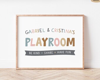 May include: A framed print with the words "GABRIEL & CRISTINA'S PLAYROOM" in colorful letters. Below the text is a banner that reads "BE KIND • SHARE • HAVE FUN". The frame is a light brown color.