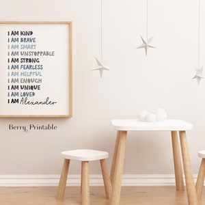 May include: A framed print with a white background and blue and gray text that reads "I am kind, I am brave, I am smart, I am unstoppable, I am strong, I am fearless, I am helpful, I am enough, I am unique, I am loved, I am Alexander". The print is hanging on a white wall with a small wooden table and two stools in front of it.