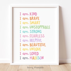 May include: A white framed print with a rainbow colored list of positive affirmations. The text reads "I am KIND, I am BRAVE, I am SMART, I am UNSTOPPABLE, I am STRONG, I am FEARLESS, I am HELPFUL, I am BEAUTIFUL, I am UNIQUE, I am LOVED, I am MADISON".