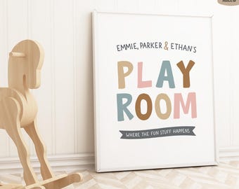 May include: A white framed print with the text "EMMIE, PARKER & ETHAN'S PLAY ROOM WHERE THE FUN STUFF HAPPENS" in colorful letters. The letters are in shades of brown, pink, and blue.