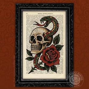 May include: A framed art print featuring a vintage book page background with a central illustration of a beige human skull entwined by a green and yellow snake with a red tongue, positioned above a large red rose with dark green leaves.