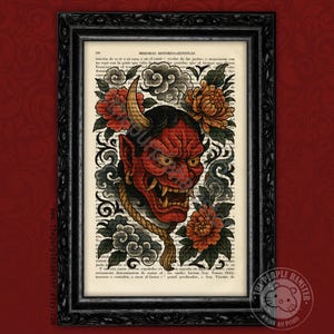Op de afbeelding: Ingelijste kunstprint met een rood Oni-masker met hoorns, omringd door bloemen- en wolkenmotieven. Het kunstwerk is geplaatst tegen een achtergrond van oude boekpagina's en is ingesloten in een zwart frame. De print heeft een tattoo-kunststijl.