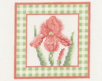 May include: A needlepoint canvas featuring a coral iris flower with green leaves. The flower is centered within a red and green gingham border, set against a white background. The design is square and detailed.