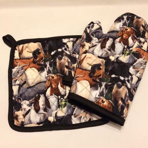 May include: A set of two black and white quilted pot holders with a goat print. The pot holders are made of fabric and have a quilted design.