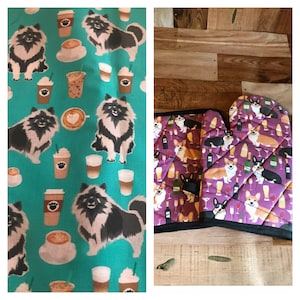 May include: A set of two kitchen towels featuring a teal background with a repeating pattern of black and white dogs, coffee cups, and coffee beans. A second set of two oven mitts features a purple background with a repeating pattern of black and white dogs, wine glasses, and wine bottles.