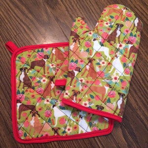 May include: A set of green and red quilted kitchen pot holders with a floral pattern and boxer dog illustrations.