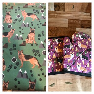 May include: Two fabric patterns. One features German Shepherds, boots, mountains, compasses, and footprints on a green background. The other shows Corgi dogs, wine bottles, glasses, and martini glasses on a purple background. A quilted oven mitt is also visible.