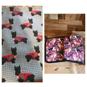 Pode incluir: Um conjunto de dois pegadores de panela roxos com um padrão de corgis usando chapéus de festa e segurando bebidas. Os pegadores de panela estão sobre uma superfície de madeira.