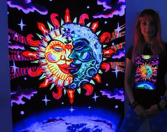 May include: A black tapestry with a glow-in-the-dark design of a sun and moon with a third eye and an Om symbol. The tapestry is hanging on a wall and a person is standing in front of it. The person is wearing a black shirt with a similar design to the tapestry.