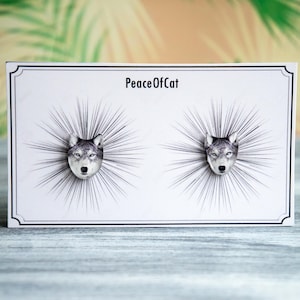 May include: A pair of wolf head earrings on a white card with the text "PeaceOfCat".