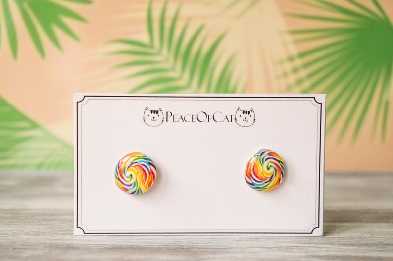 May include: A pair of rainbow swirl lollipop stud earrings on a white card with the text "Peace of Cat".