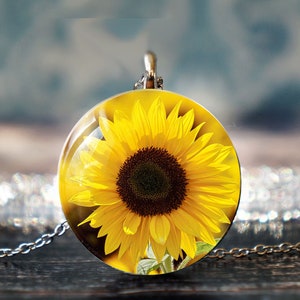 May include: A silver chain necklace with a round glass pendant featuring a yellow sunflower.