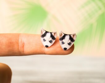 May include: A pair of small, white and black husky dog earrings. The earrings are made of polymer clay and are about the size of a dime.