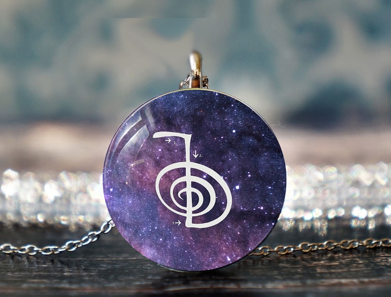 May include: A silver chain necklace with a round pendant featuring a white symbol on a purple and blue galaxy background.