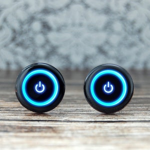 Peut inclure: Deux boutons ronds noirs avec un symbole d'alimentation bleu à l'intérieur d'un cercle bleu.