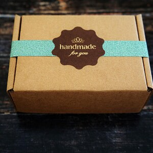 May include: A brown cardboard box with a blue and white ribbon and a brown sticker that says "handmade for you".