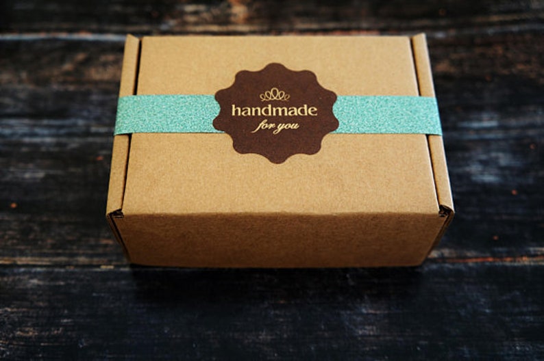 May include: A brown cardboard box with a blue and white ribbon and a brown sticker that says "handmade for you".