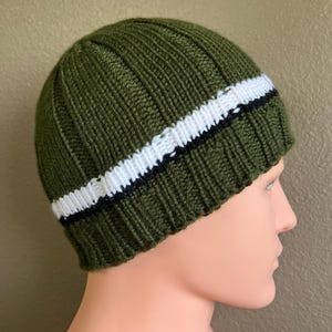 May include: A green knitted beanie with a white and black stripe.