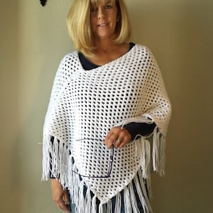 Può includere: Poncho in crochet bianco con frange. Il poncho ha una vestibilità ampia e un'ampia scollatura.