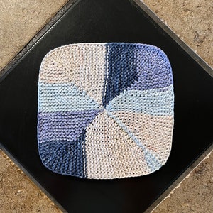 May include: A square knitted dishcloth with a geometric pattern in shades of blue and beige.