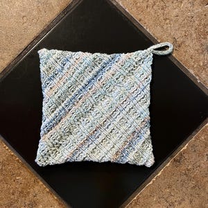 May include: A blue, green, and beige crocheted pot holder with a loop handle.