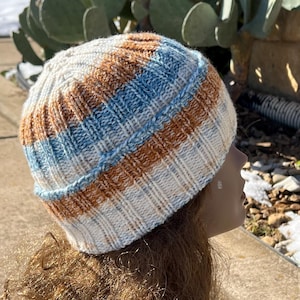 May include: A white, blue and brown striped knitted beanie hat.