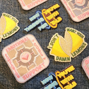May include: A collection of embroidered iron-on patches with various phrases and designs. The patches feature a variety of colors, including pink, yellow, blue, green, and white. The patches are perfect for adding a unique touch to clothing, bags, or other accessories.