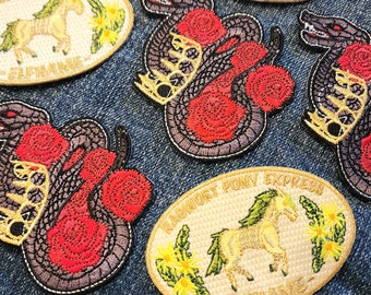 May include: A collection of embroidered iron-on patches featuring a black snake with red roses, a white pony with green leaves, and the text "Ragnarok Pony Express" in gold thread.