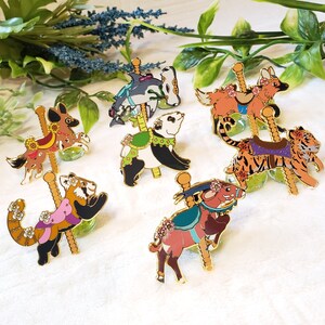 K&ouml;nnte beinhalten: Ein Set mit zehn Emaille-Pins, die verschiedene Tiere zeigen, die auf einem Karussell reiten. Die Pins sind farbenfroh und detailliert, jedes Tier hat ein einzigartiges Design. Die Pins sind perfekt, um jedem Outfit oder jeder Tasche einen Hauch von Verspieltheit zu verleihen.