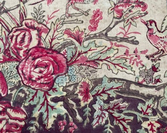 Puede incluir: Una tela vintage con un diseño floral y de pájaros. La tela presenta rosas rosas y rojas, hojas verdes y dos pájaros con plumas rojas y marrones. La tela tiene un fondo blanco con un borde morado oscuro.