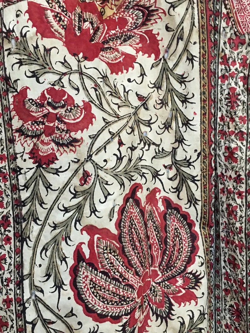 Pu&ograve; includere: Un tessuto bianco con un motivo floreale rosso e nero. I fiori sono stilizzati e hanno un design di tipo paisley. Il tessuto ha un aspetto e una sensazione vintage.