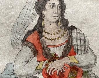 May include: A woman wearing a red and yellow patterned head covering with a floral embellishment. She is wearing a red and white patterned dress with a fur trim and a green and white patterned shawl. She is holding a red and gold patterned object in her lap.
