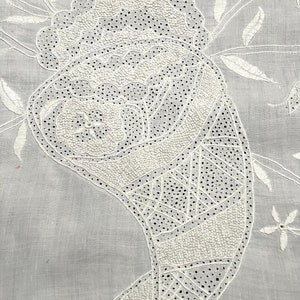 May include: White cotton fabric featuring a detailed white embroidery design of a paisley shape. The embroidery is executed with a fine stitch, creating a delicate and intricate pattern.