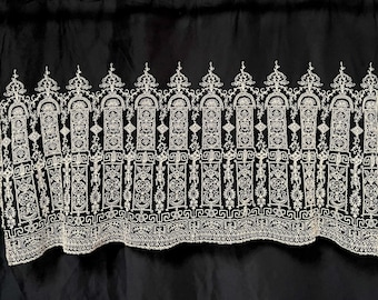 May include: A black fabric with an intricate, white embroidered design. The pattern features repeating arched shapes, geometric patterns, and floral elements. The design is symmetrical and detailed, creating a decorative border.