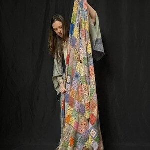 May include: A colorful crocheted patchwork blanket with a variety of colors, including blue, green, yellow, orange, and pink. The blanket is made of a soft, lightweight yarn and has a delicate, lacy texture.