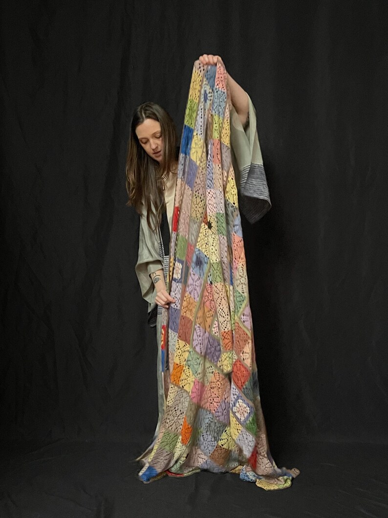 May include: A colorful crocheted patchwork blanket with a variety of colors, including blue, green, yellow, orange, and pink. The blanket is made of a soft, lightweight yarn and has a delicate, lacy texture.