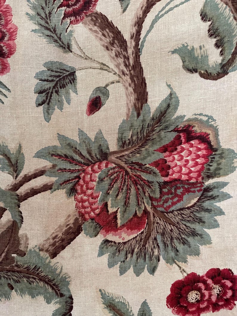 May include: A vintage floral fabric with a cream background and a repeating pattern of red and green flowers. The flowers are stylized and have a slightly abstract look. The fabric has a linen texture.