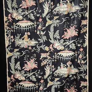 May include: A black fabric with a repeating pattern of pink and green flowers, birds, and figures in a Chinese garden setting.